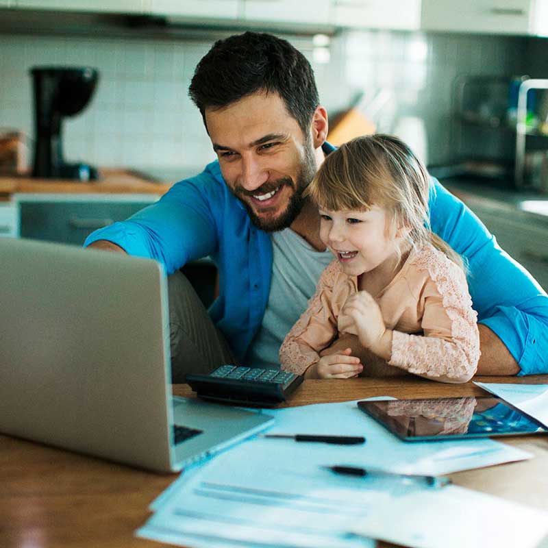 man with his daughter smiling while looking in the computer screen